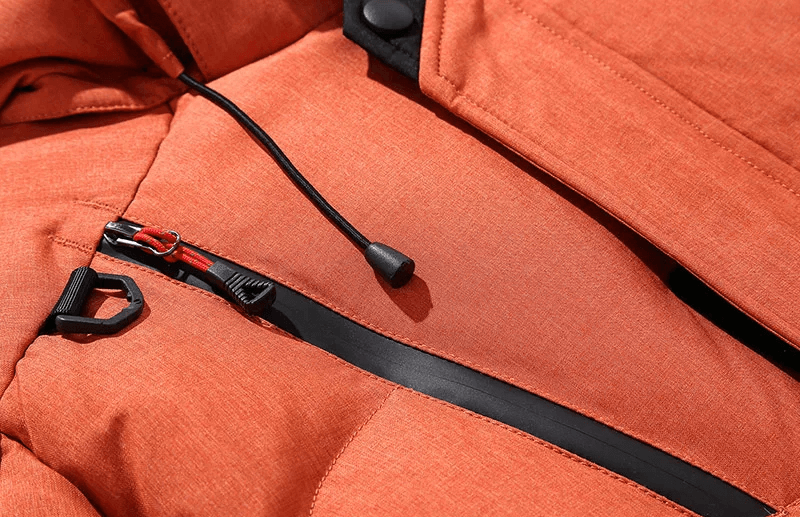 Close-up of orange windproof ski jacket with zipper, showcasing durable fabric and black accents.