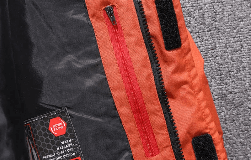 Close-up of windproof orange and black ski jacket with zipper and velcro details, perfect for skiing and winter sports.