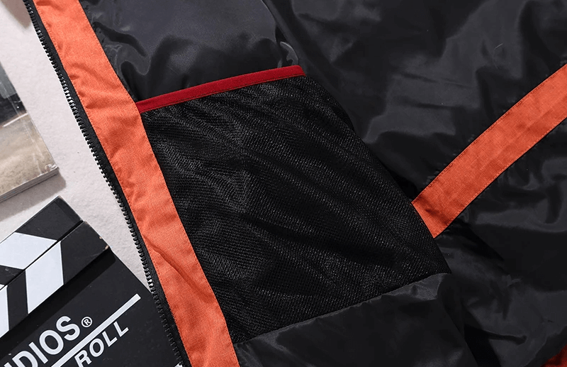 Men's Windproof Ski Suit detail showing black and orange fabric with jacket pocket, highlighting quality and style.