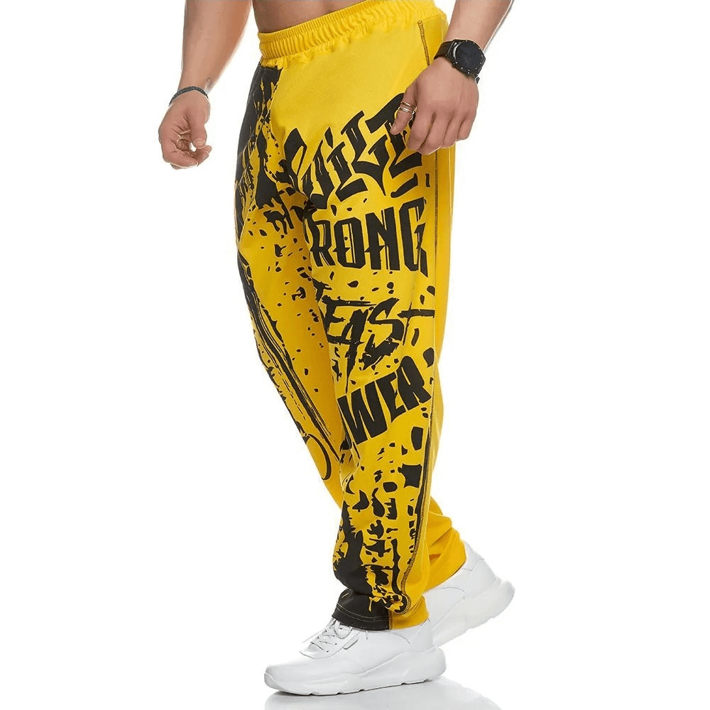 Men's yellow drip print joggers, sporty look, white sneakers. Stylish gym sweatpants for men, athletic and comfortable design.
