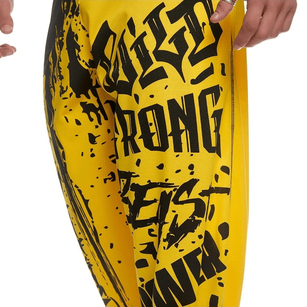 Close-up of yellow men's athletic drip print sweatpants with bold black graphics, perfect for gym workouts and stylish streetwear.