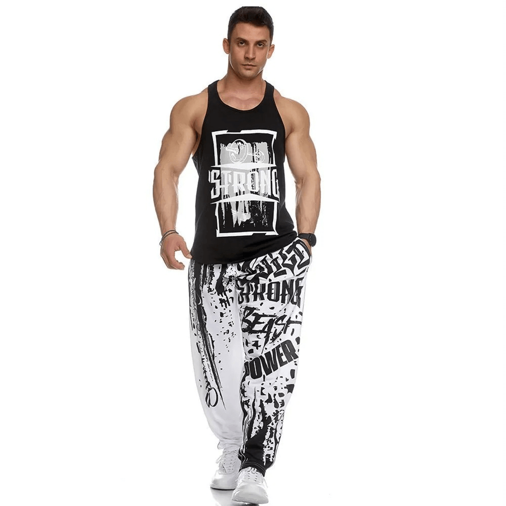 Man wearing men's athletic drip print sweatpants and black tank top, showcasing gym joggers ideal for workouts and running.