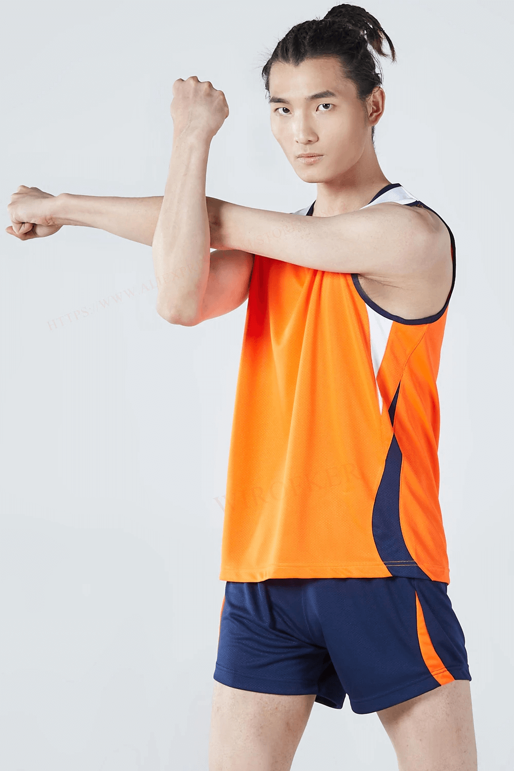 Athletic man in orange mesh tank and navy shorts, stretching arms in quick-drying running set, perfect for workouts and sports.