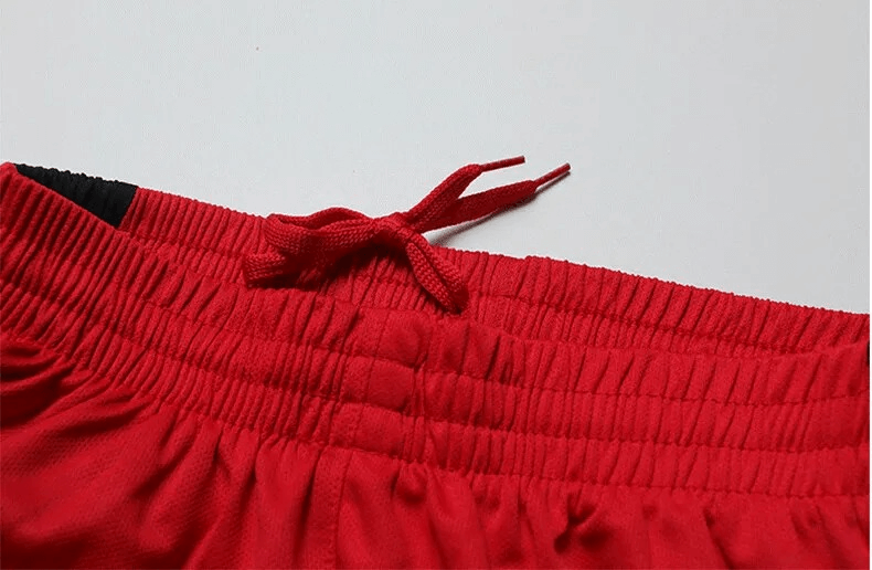 Close-up of neon red elastic waistband with drawstrings on men's soccer shorts, showcasing lightweight and durable material.
