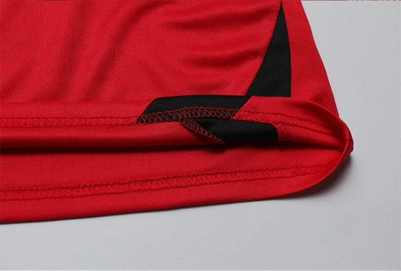 Close-up of red and black soccer jersey hem, showcasing sleek stitching and moisture-wicking fabric for optimal athletic performance.