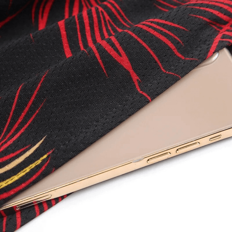 Close-up of pocket detail on men's basketball sports board shorts with a smartphone inside, showcasing the red and black print design.