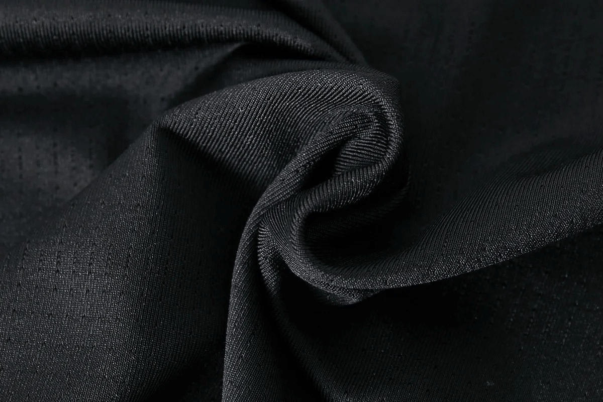 Close-up of black polyester fabric twisted to form a swirl, showcasing texture and flexibility for athletic wear.