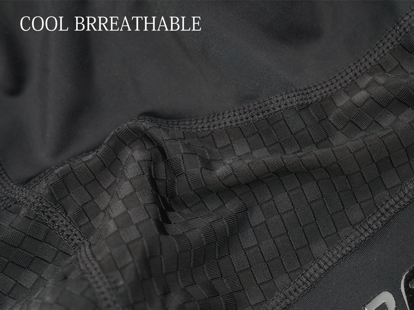 Men's cycling shorts fabric close-up showcasing breathable, cool material with a textured pattern and stitching details.