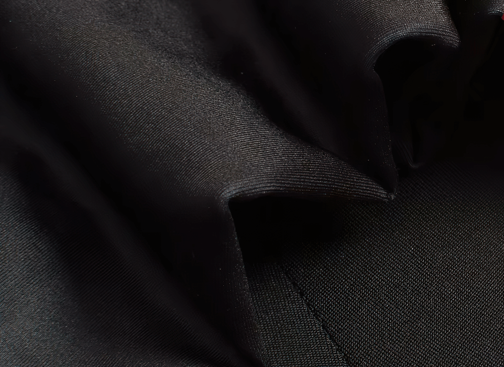 Close-up of smooth black fabric texture, highlighting its soft and shiny appearance, ideal for fashion or textile design.