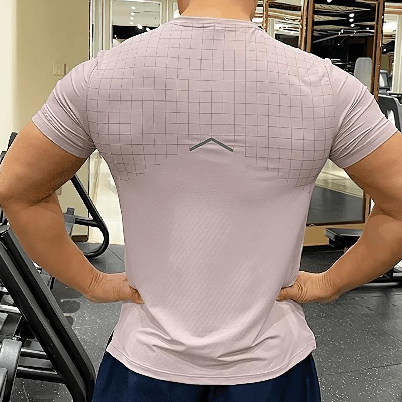 Man wearing Men's Grid-Print Quick-Dry Gym Tee in gym setting with exercise equipment visible.