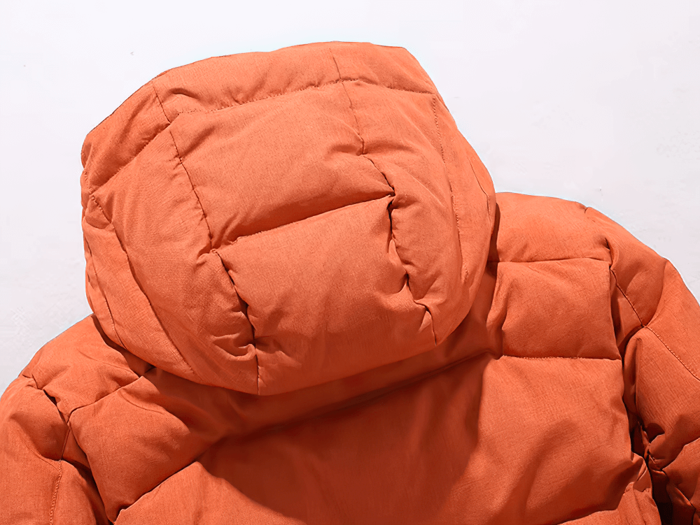 Close-up of orange hooded duck down jacket with detachable hood and warm, thick padding for winter.