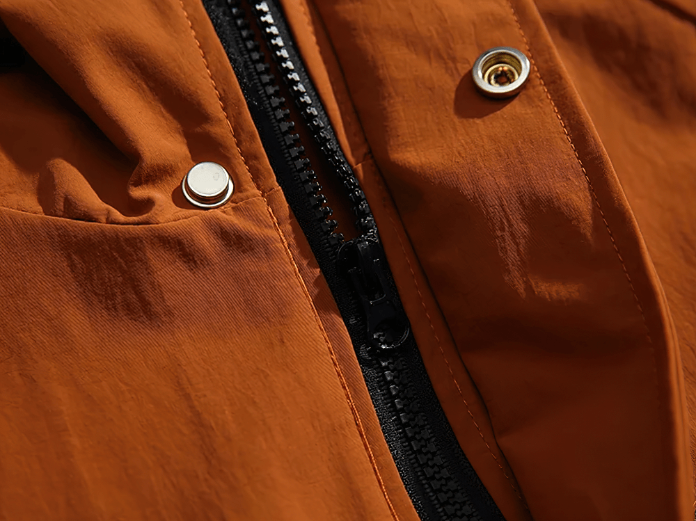 Close-up of a rugged orange men's utility jacket with zipper and snap buttons, showcasing its durable fabric and detailed design.