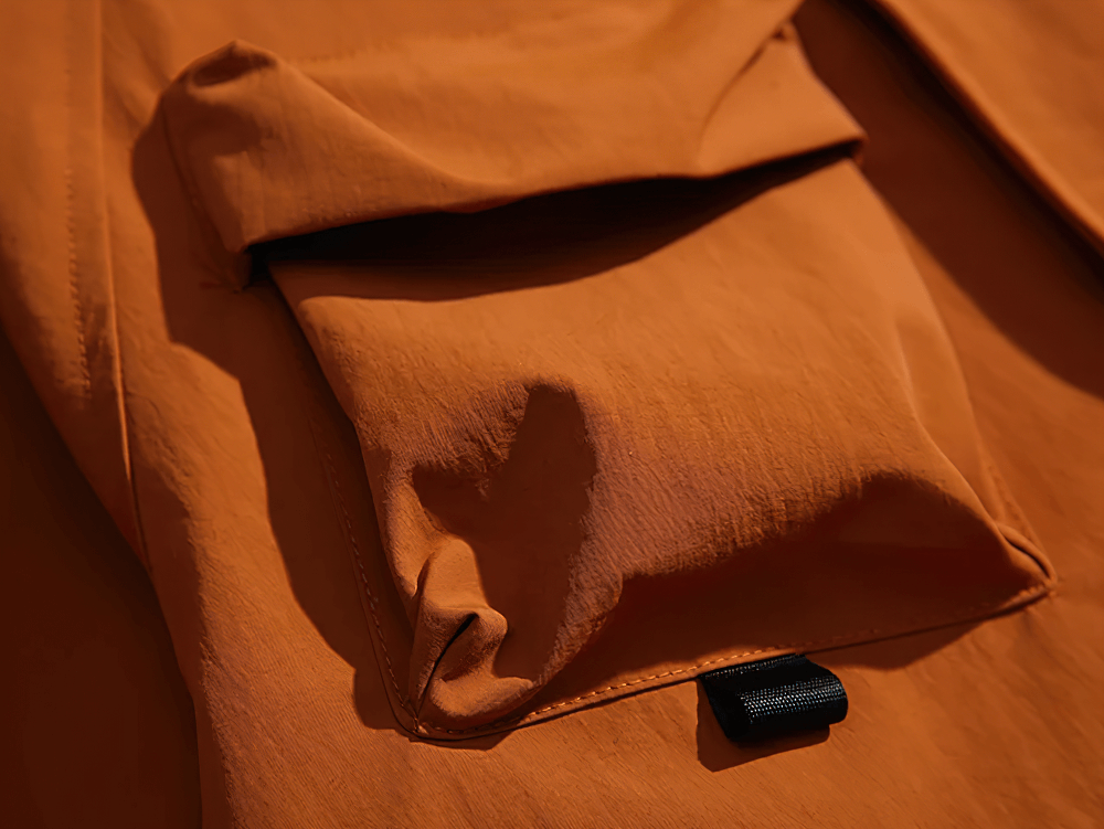 Close-up of a durable men's hooded jacket with a prominent multi-pocket design, showcasing rugged texture and streetwear style.