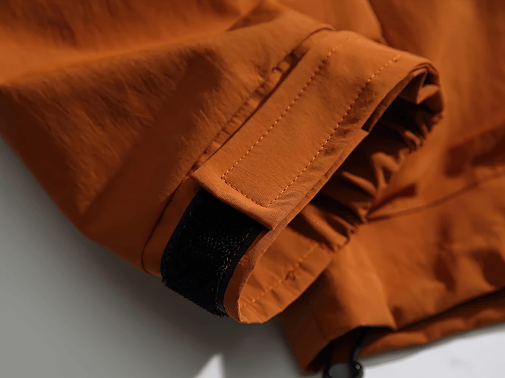 Close-up of adjustable cuff on men's tactical hooded jacket SF2263 in orange polyester, highlighting durability and streetwear style.