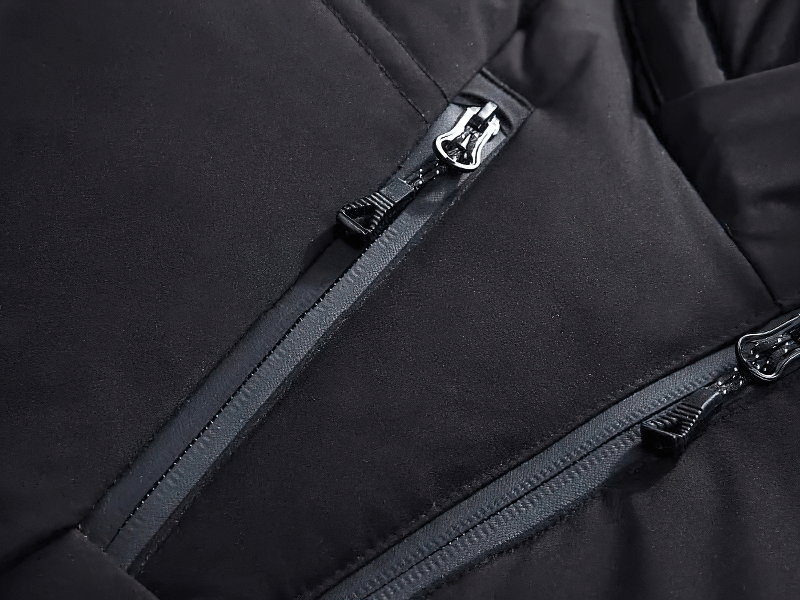 Close-up of black insulated puffer jacket with zippers, showing high-quality fabric and craftsmanship for warmth and style.