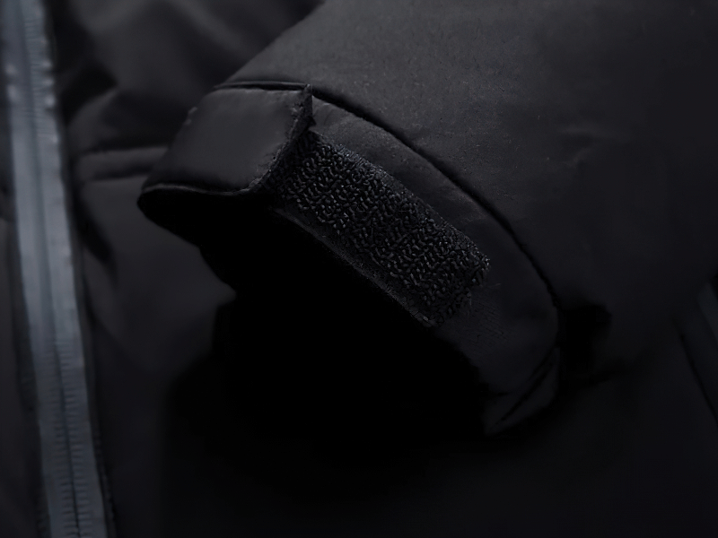 Close-up of a men's insulated puffer jacket with removable hood, showing zipper and velcro details for style and practicality.