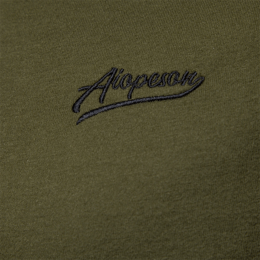 Close-up of embroidered logo on green fabric patchwork cotton top, stylish casual men's wear.