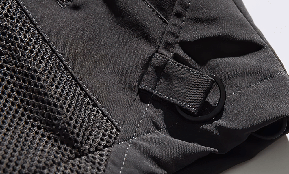 Close-up of black hiking jacket fabric detail with mesh and buckle on cuff.