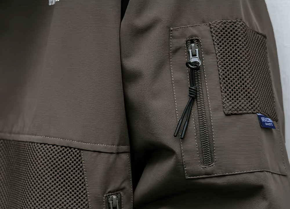 Close-up of brown men's hiking jacket with zippered pocket, durable mesh design, and waterproof fabric - perfect for outdoor adventures.
