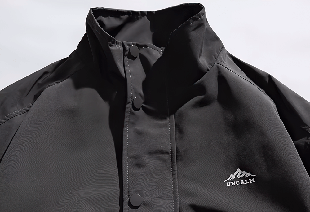 Men's black waterproof hiking jacket with stand collar and button closure, ideal for urban and trail adventures.