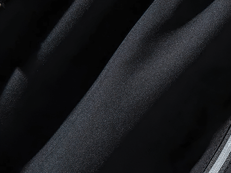 Close-up of black men's quick-dry gym shorts fabric with a textured finish and a zipper pocket edge.