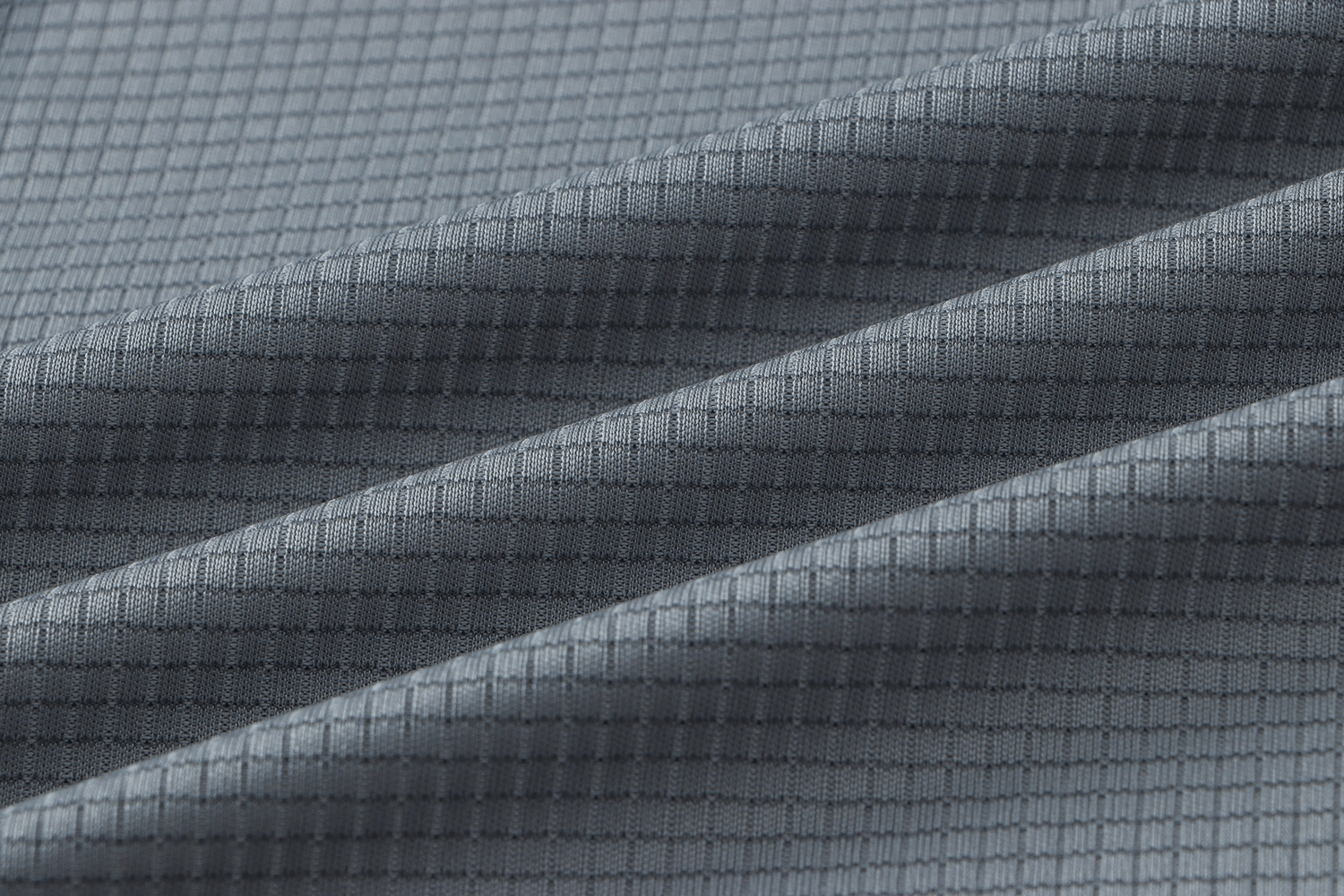 Close-up of gray quick-drying polyester fabric texture, highlighting breathable sportswear material used in men's training t-shirts.