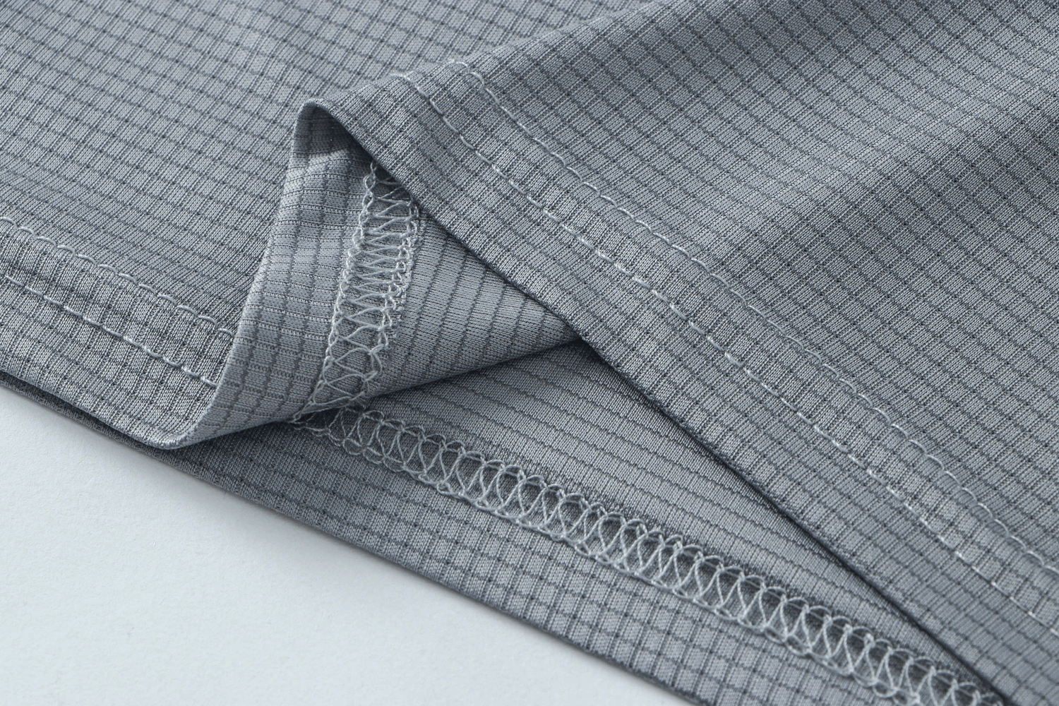 Close-up of gray polyester quick-dry T-shirt fabric showing stitching details, perfect for athletic training and sports.