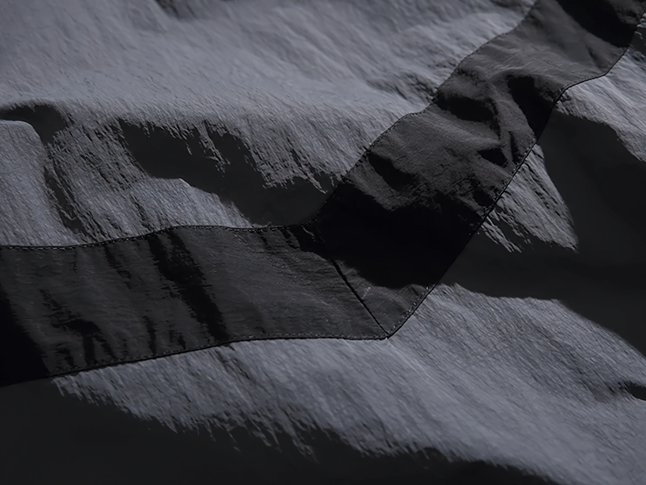 Close-up of reflective strip patchwork on a men's nylon jacket, showcasing streetwear style and durability.