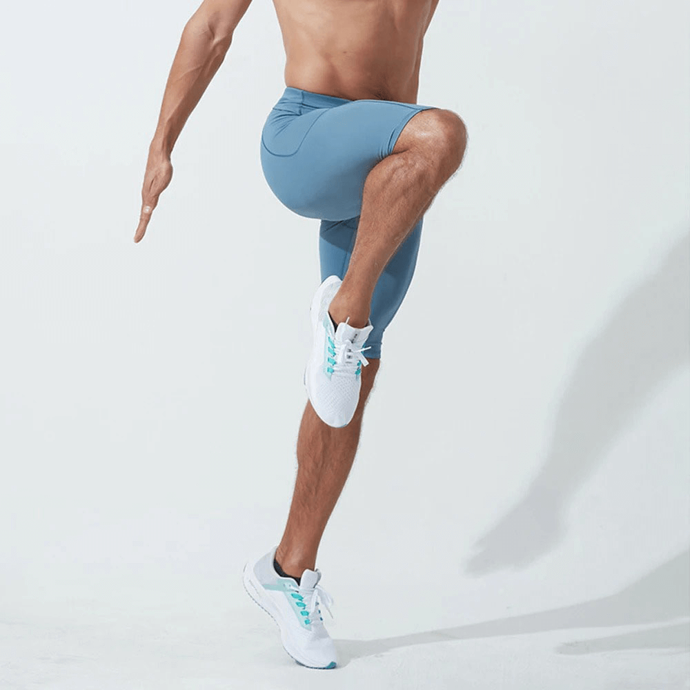 Man exercising in blue running compression shorts with pockets, demonstrating mobility and style.