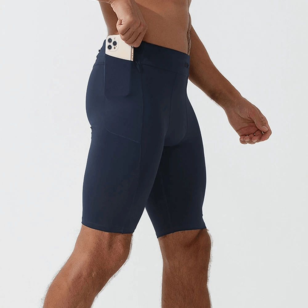 Men's navy running compression shorts with pockets holding a phone, made from breathable nylon and spandex for optimal comfort and style.
