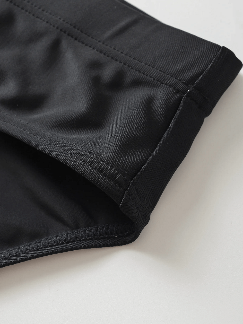 Close-up of black men's swim briefs with drawstring waistband, showcasing durable fabric and sleek design for stylish beachwear.