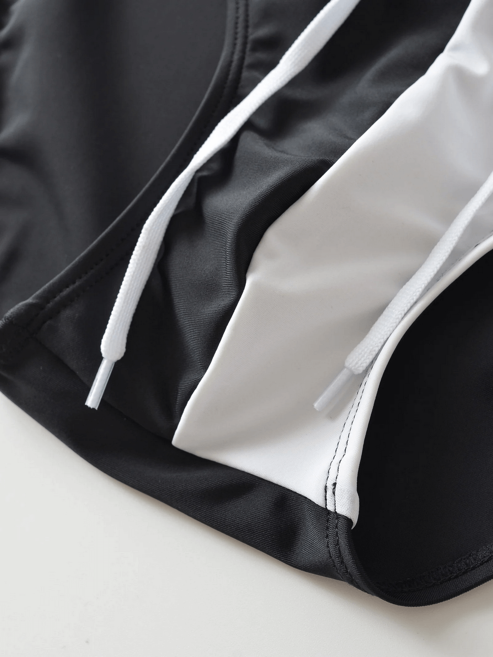 Close-up of men's swim briefs with drawstring waistband, showcasing sleek design and durable material in black and white.