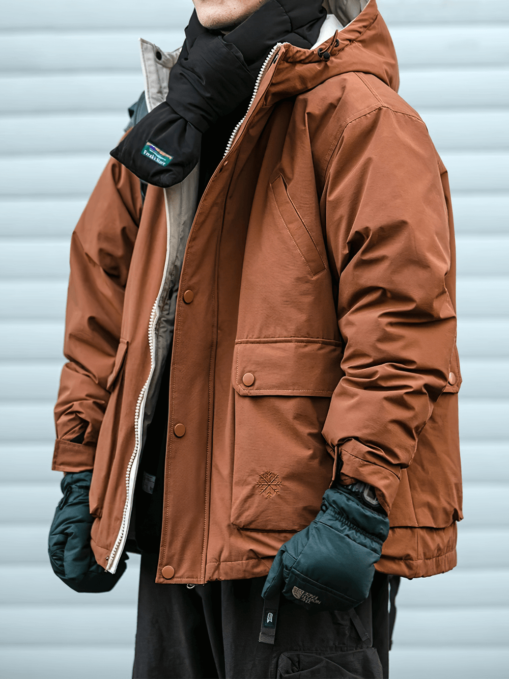 Man wearing a thick brown hooded winter jacket, ideal for outdoor adventures and streetwear, with windproof design and practical zip closure.