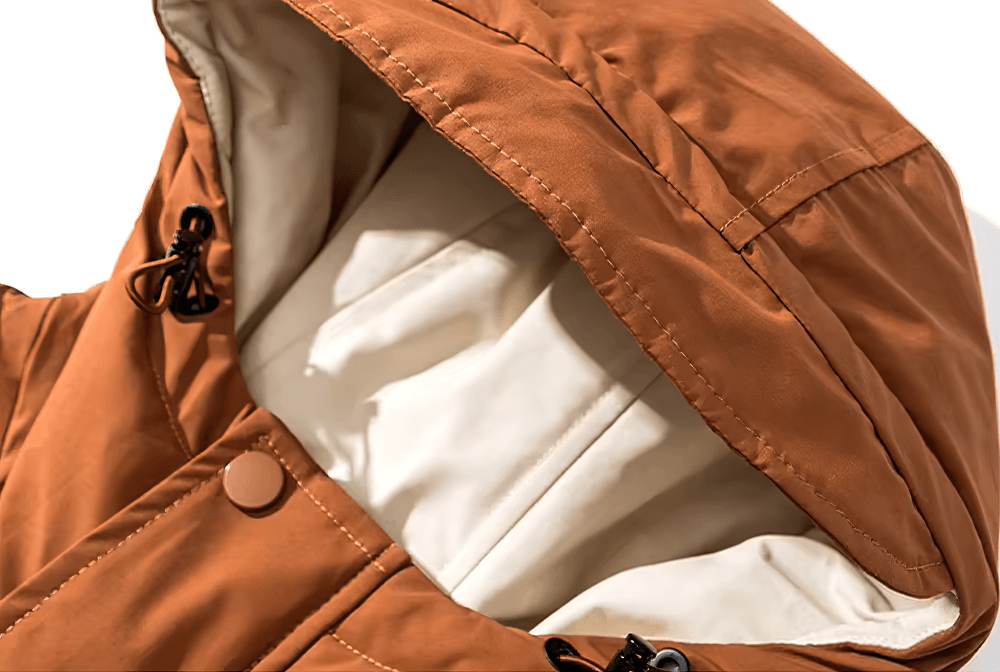 Close-up of men's brown hooded duck down winter jacket, showcasing lined hood and windproof cotton fabric for outdoor adventures.
