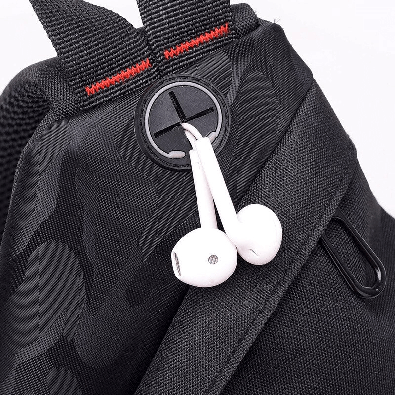 Close-up of a waterproof camouflage crossbody bag with earphones looped through the headphone port.