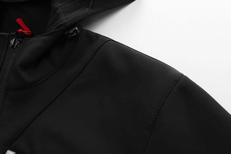 Close-up of black waterproof softshell jacket with hood, highlighting sleek stitching and modern design, perfect for outdoor sports.