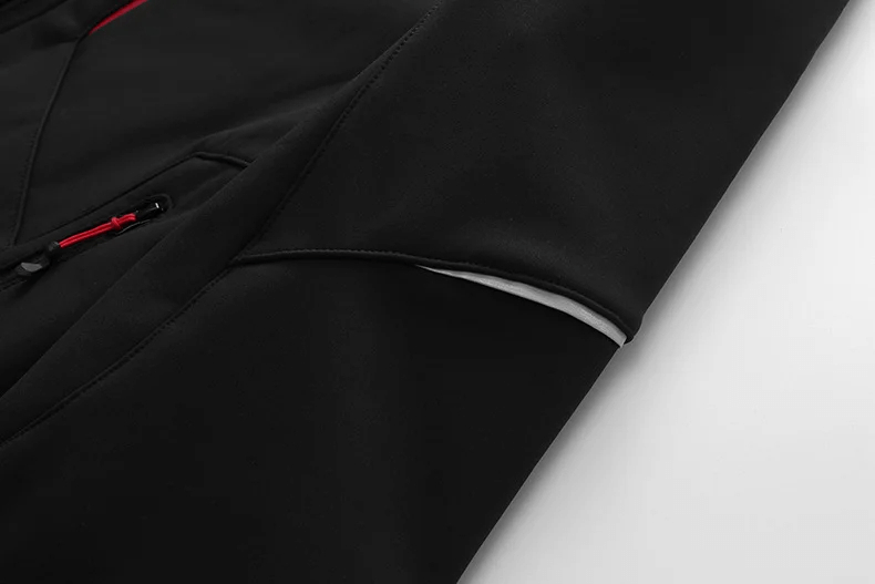 Close-up of black waterproof softshell jacket sleeve with detail of red stitching, showcasing sleek design and durable material.