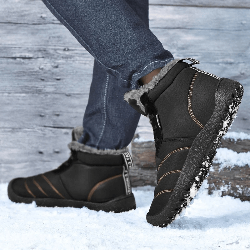 Man wearing Men's Winter Ankle Snow Boots SF2026 on snowy terrain, showcasing black split leather and rugged rubber outsole.