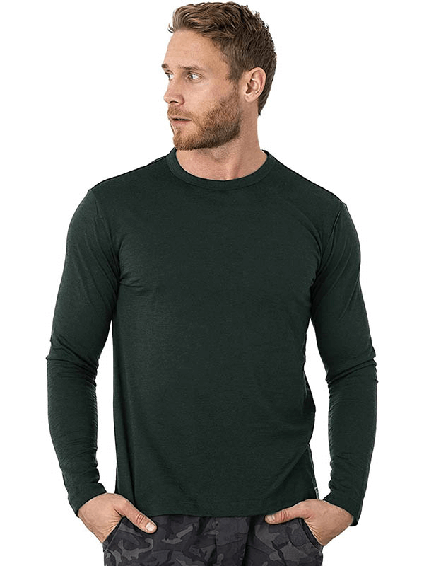 Man wearing merino wool thermal long sleeve top in dark green, offering warmth and comfort with a stylish look.