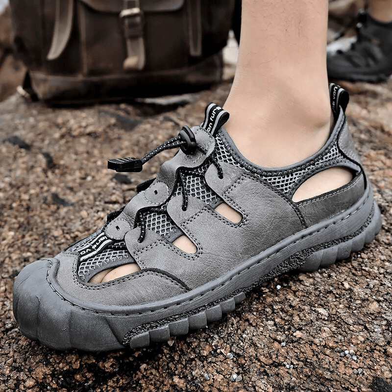 Gray mesh breathable men's sandals with flexible sole, genuine leather upper, low heel, and rubber outsole for grip on rugged surface.