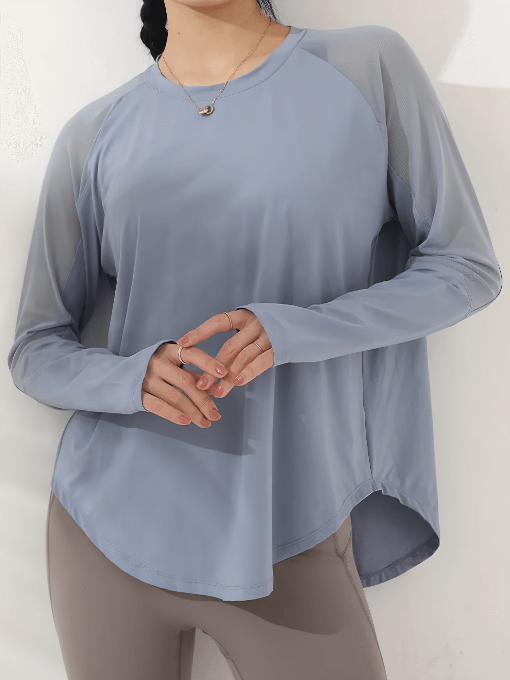 Woman wearing a mesh panel long-sleeved yoga top, relaxed fit, in grey color.