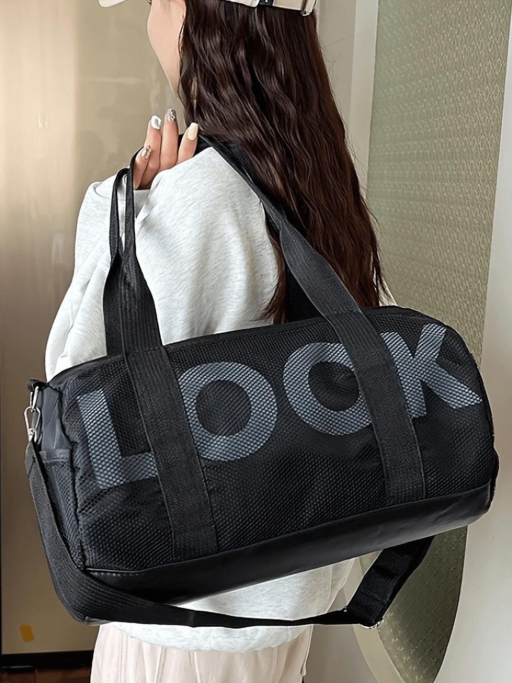 Black mesh panel sports duffel bag with 'LOOK' design, featuring side pockets and shoulder strap for gym and travel convenience.