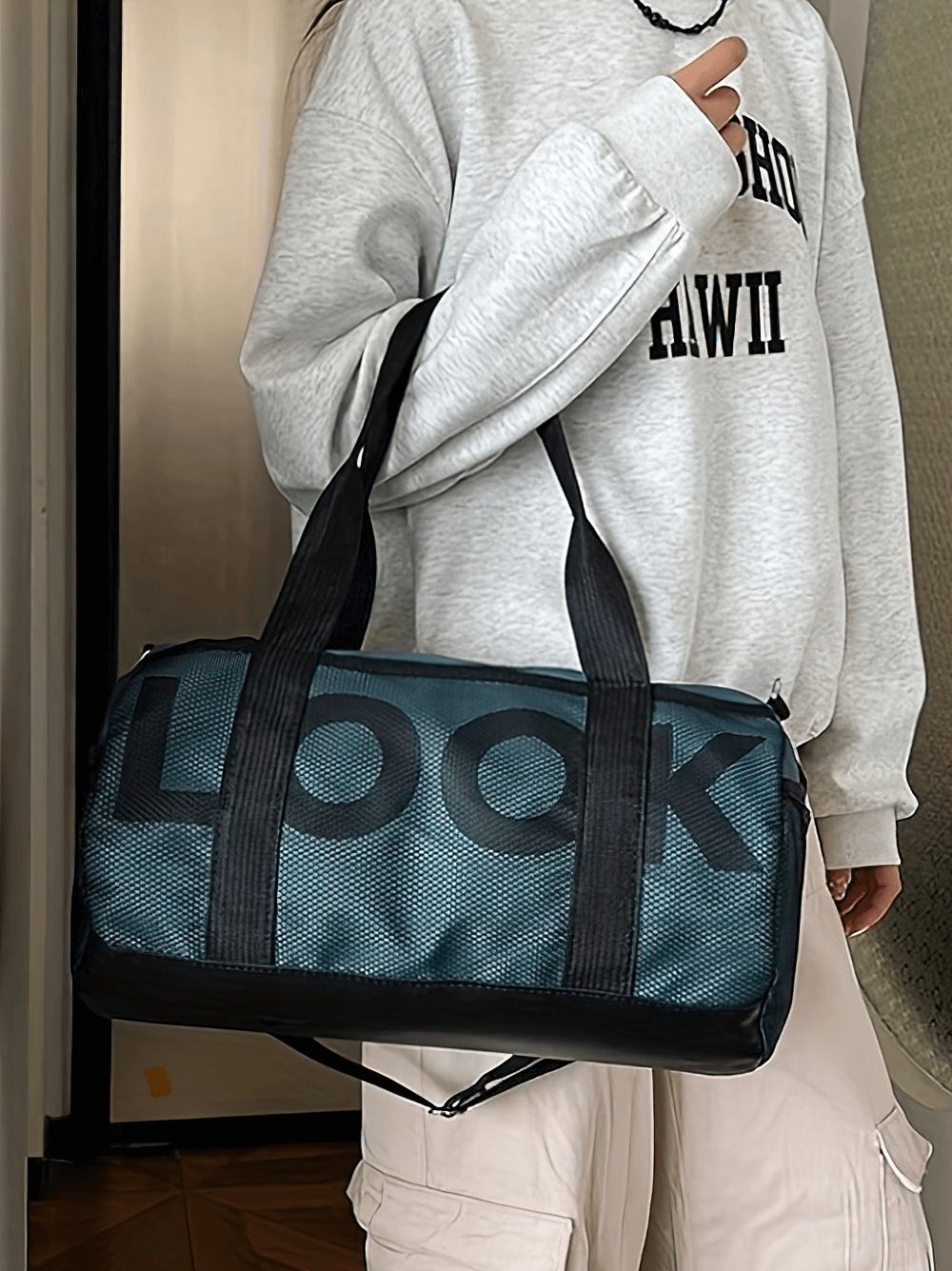 Mesh panel sports duffel bag with large capacity held by person, featuring side pockets and adjustable strap, perfect for gym and travel.