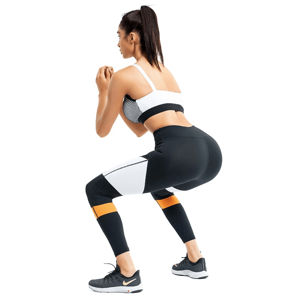 Woman wearing a beige mesh sports bra and colorblock leggings set, demonstrating flexibility and style for activewear enthusiasts.