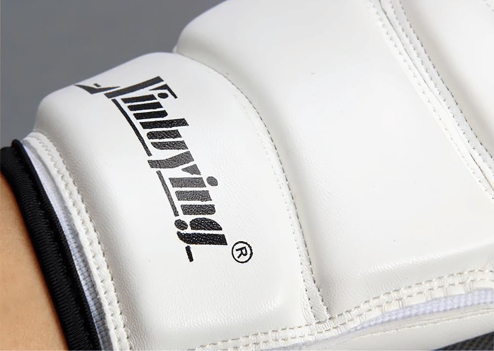 Close-up of white MMA sparring glove with EVA impact protection, showing hand stitching and branding detail.