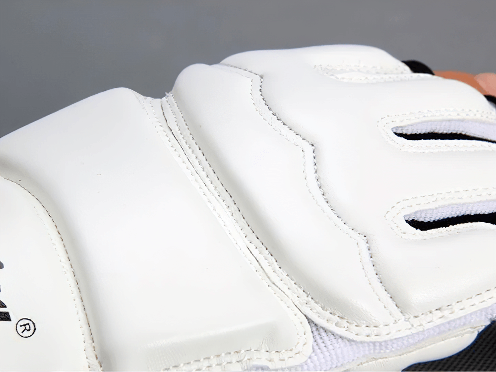 Close-up of white MMA sparring gloves with EVA impact protection and open palm design for breathability and flexibility.