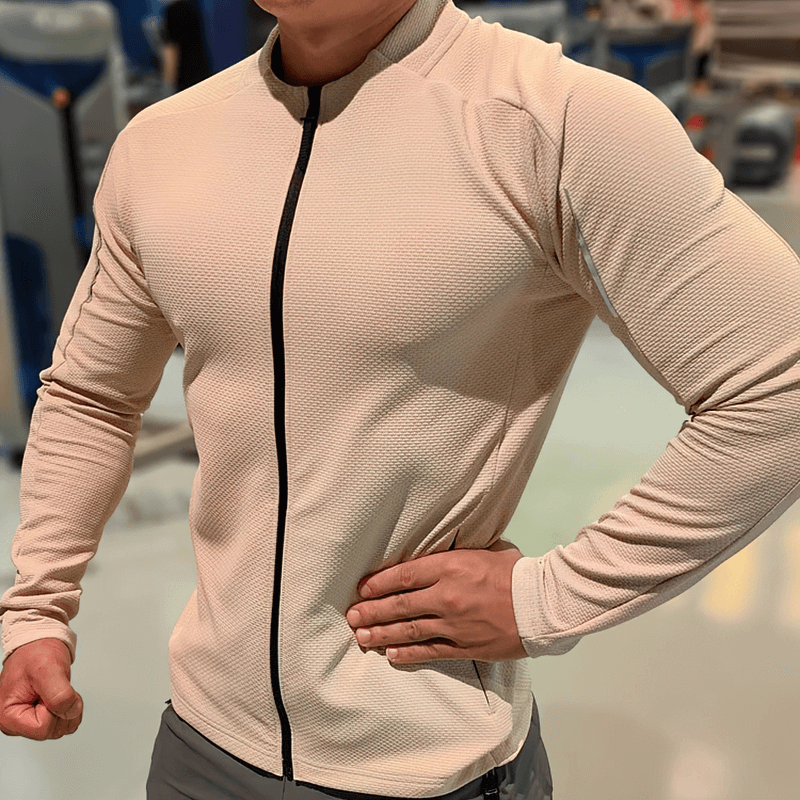 Man wearing modern zip-up textured sports jacket with pockets, perfect for running and workouts, in a gym setting.