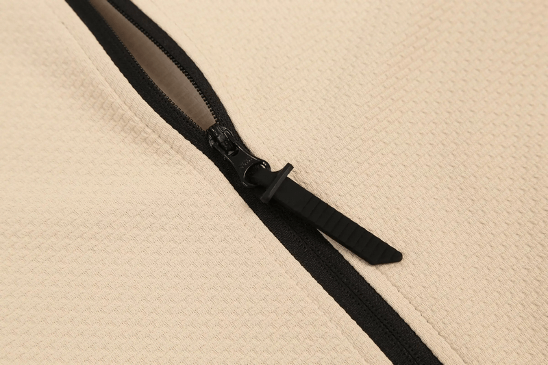 Close-up of the textured fabric and black zipper on a modern sports jacket, highlighting quality and design.