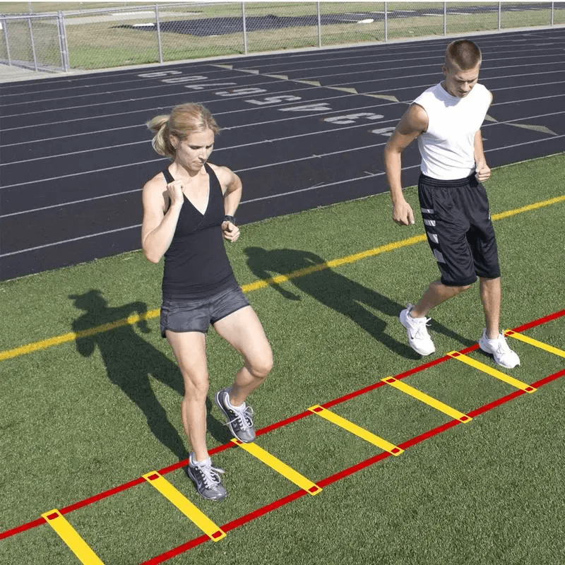 Athletes training on modular agility ladder with frosted rungs for footwork and speed drills on a track field.