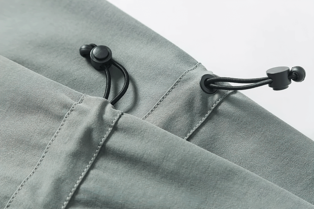 Close-up of drawstring detail on a grey utility jacket, highlighting adjustable features for versatile outdoor adventures.